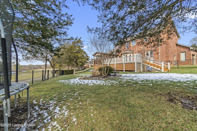 view of yard with a trampoline, a fenced backyard, stairway, and a wooden deck