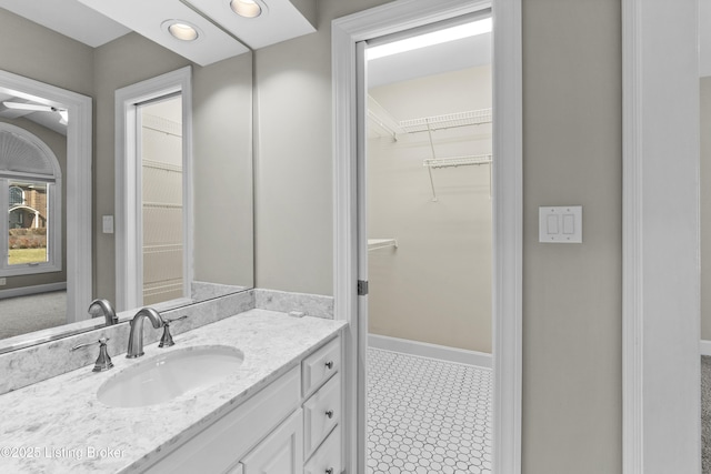 bathroom featuring a spacious closet, recessed lighting, vanity, and baseboards