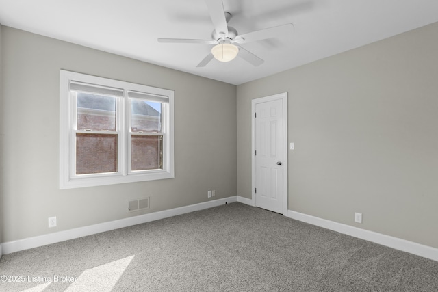 empty room featuring a ceiling fan, visible vents, carpet floors, and baseboards