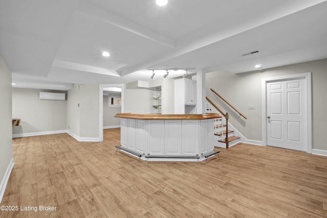 bar with a dry bar, visible vents, stairway, light wood-style flooring, and baseboards