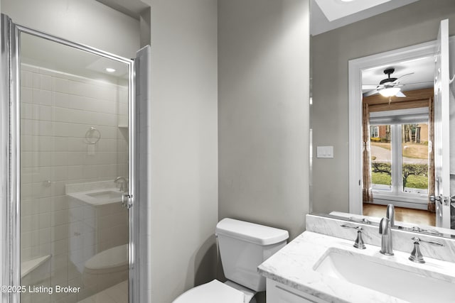 full bathroom featuring toilet, a stall shower, a ceiling fan, and vanity