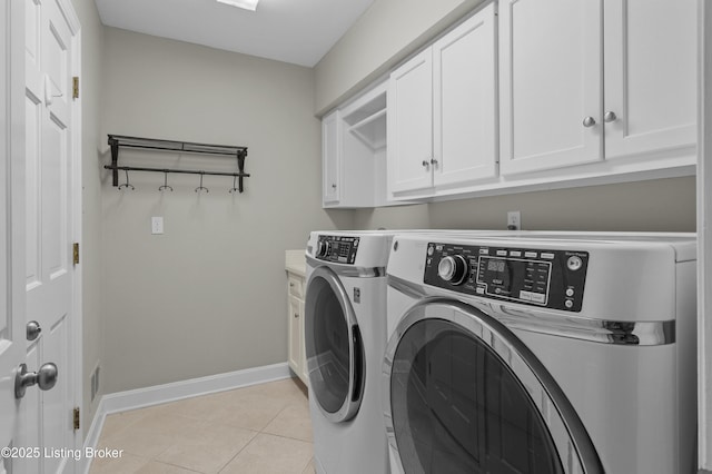 laundry room with cabinet space, light tile patterned floors, baseboards, and washer and clothes dryer