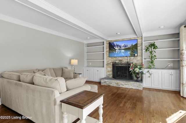 unfurnished living room with a large fireplace, wood finished floors, built in features, ornamental molding, and beam ceiling