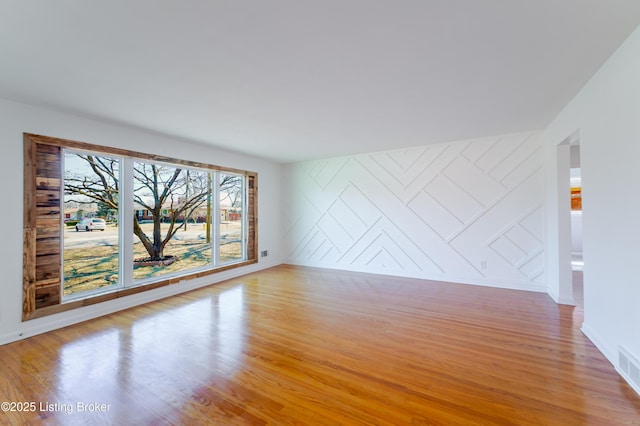 empty room with an accent wall and light wood finished floors