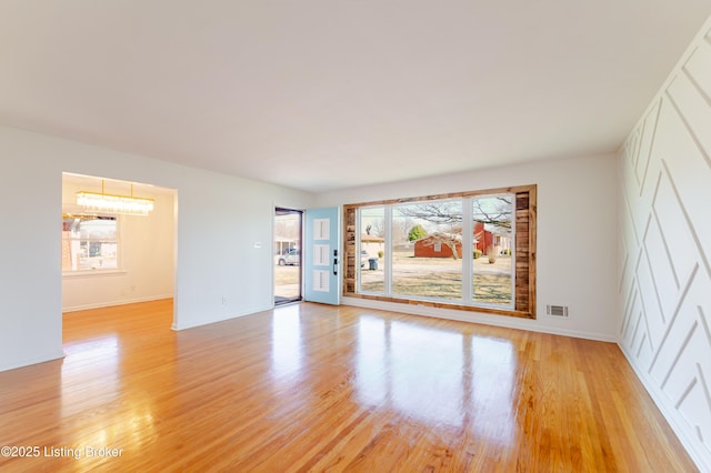 empty room featuring light wood-style floors, baseboards, and visible vents