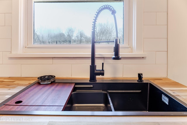 room details with butcher block counters, decorative backsplash, and a sink