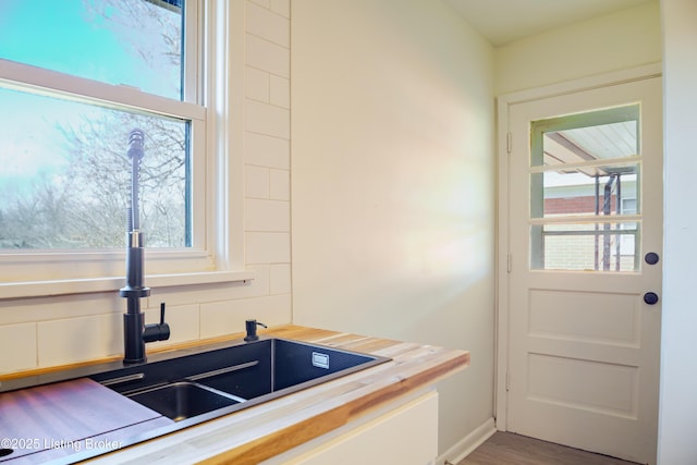 kitchen with tasteful backsplash, a sink, wood counters, and wood finished floors