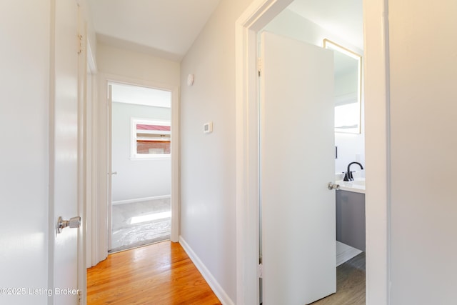 corridor with light wood-style flooring and baseboards