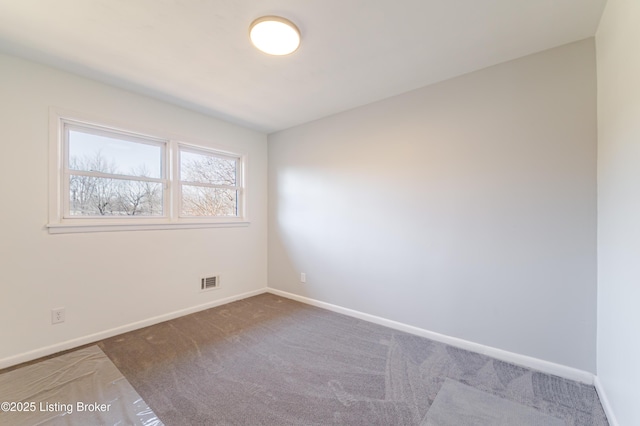 empty room with carpet flooring, visible vents, and baseboards