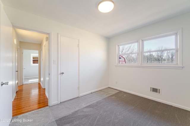 unfurnished bedroom featuring carpet floors, visible vents, and baseboards