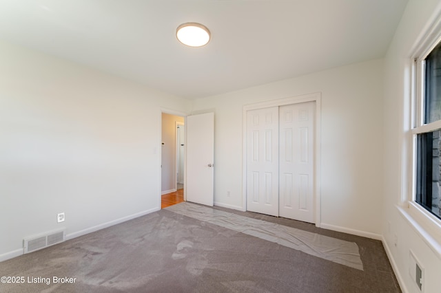 unfurnished bedroom featuring baseboards, a closet, visible vents, and carpet flooring