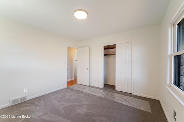 unfurnished bedroom with carpet, a closet, visible vents, and baseboards