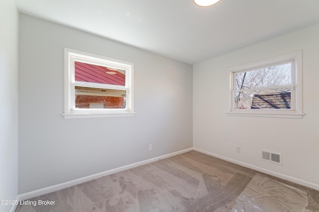 empty room with carpet, visible vents, and baseboards