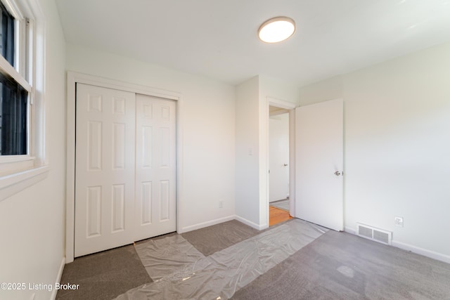 unfurnished bedroom featuring baseboards, a closet, visible vents, and carpet flooring