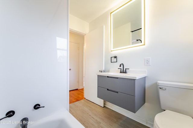 full bathroom featuring a washtub, toilet, vanity, wood finished floors, and walk in shower