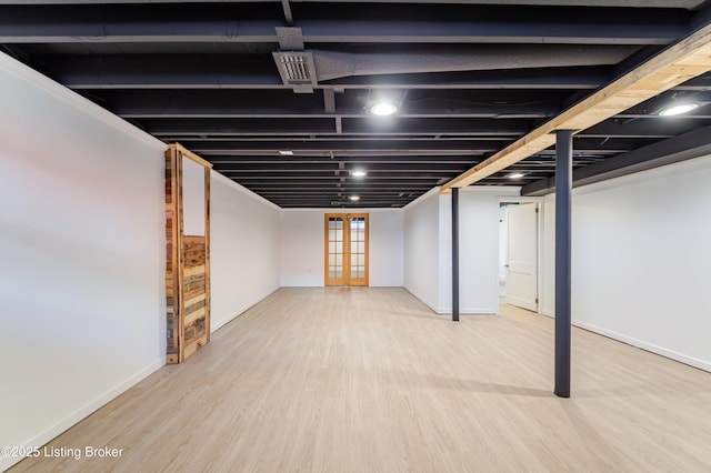 below grade area featuring french doors, baseboards, and wood finished floors