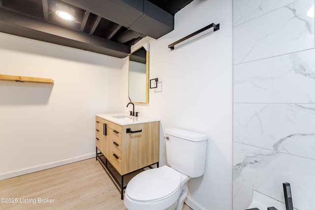 bathroom featuring toilet, wood finished floors, vanity, and baseboards