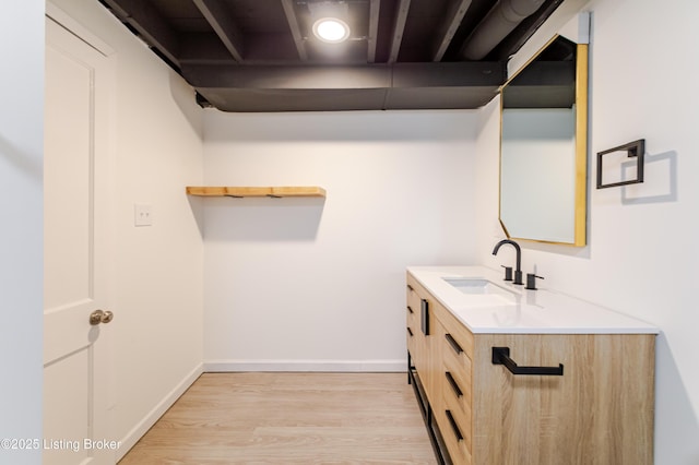 laundry room with light wood finished floors, a sink, and baseboards