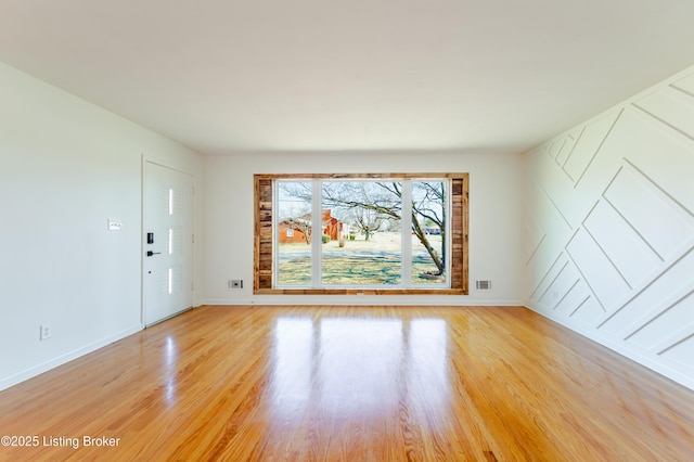 unfurnished room with light wood-style floors, visible vents, and baseboards