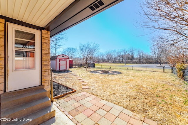 view of yard with entry steps, an outdoor fire pit, a fenced backyard, an outdoor structure, and a shed