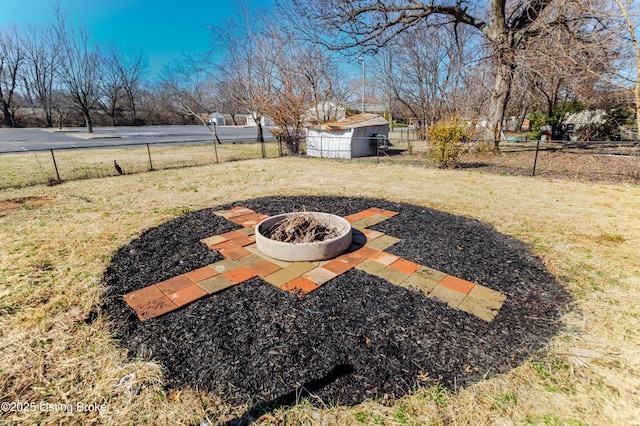 view of yard featuring a fire pit, fence, and an outdoor structure