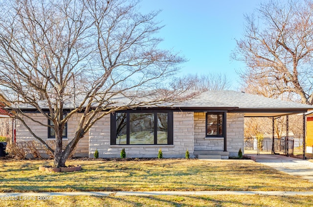 view of front of home featuring fence, an attached carport, stone siding, driveway, and a front lawn