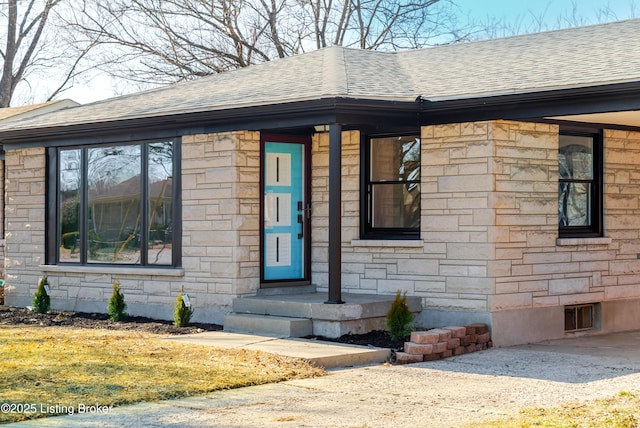 property entrance featuring a shingled roof and stone siding