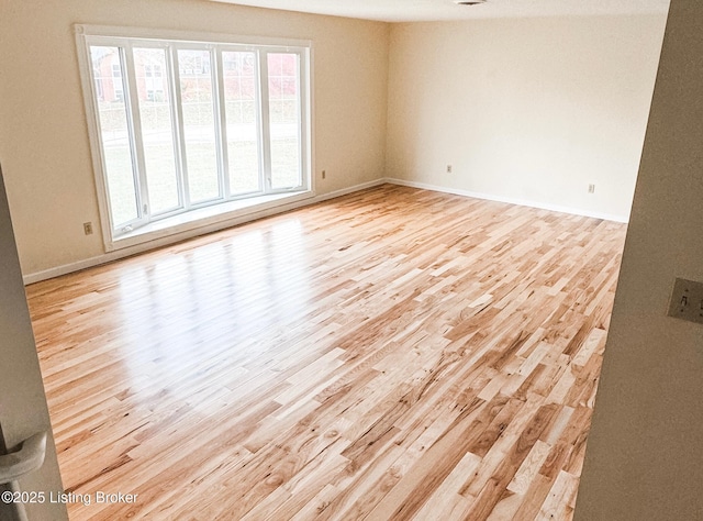 spare room featuring light wood-style floors and baseboards