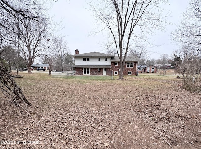 rear view of house with brick siding, fence, and a chimney