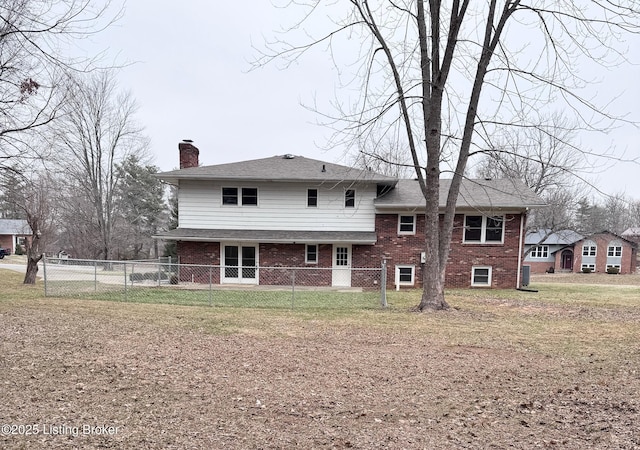 back of house with brick siding, a chimney, fence, and a lawn