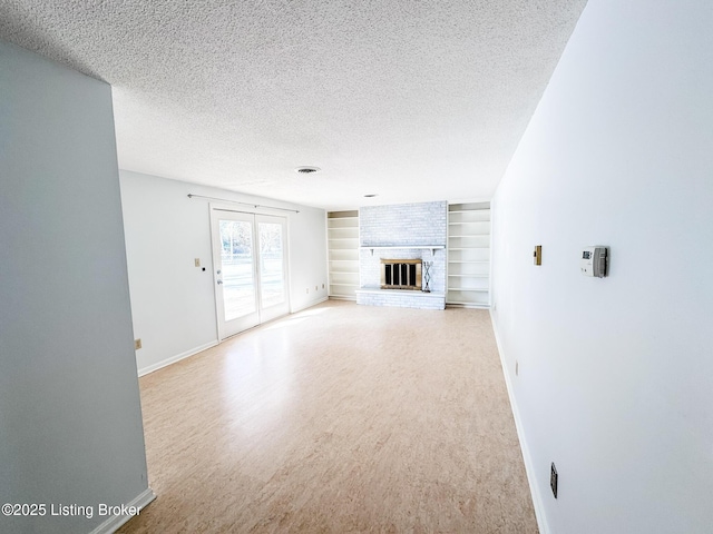 unfurnished living room featuring a textured ceiling, baseboards, built in features, a brick fireplace, and light wood finished floors