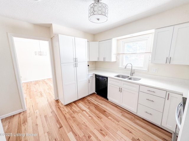 kitchen featuring black dishwasher, light countertops, a sink, and white cabinetry