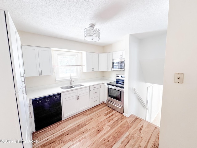 kitchen featuring stainless steel appliances, light countertops, light wood-type flooring, white cabinetry, and a sink