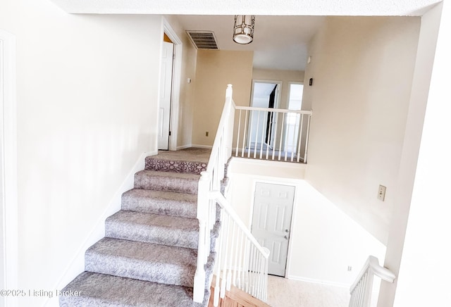 staircase featuring visible vents and baseboards