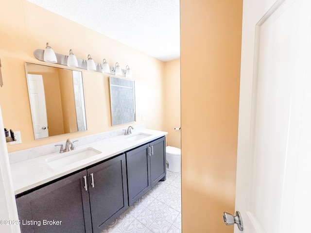 bathroom with a sink, toilet, and double vanity