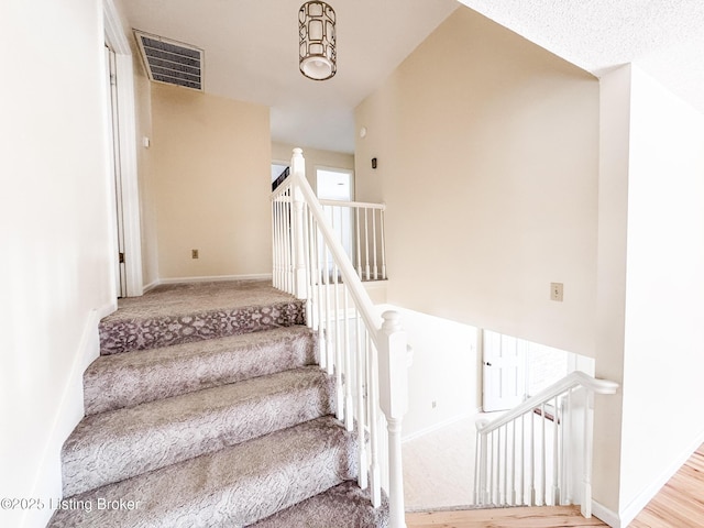 stairs with carpet, visible vents, and baseboards