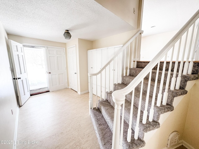 entryway featuring stairs, baseboards, and a textured ceiling