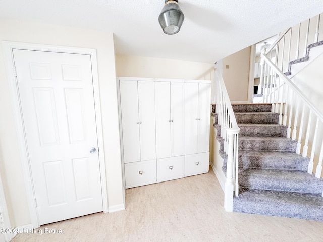 stairs with a textured ceiling, baseboards, and wood finished floors