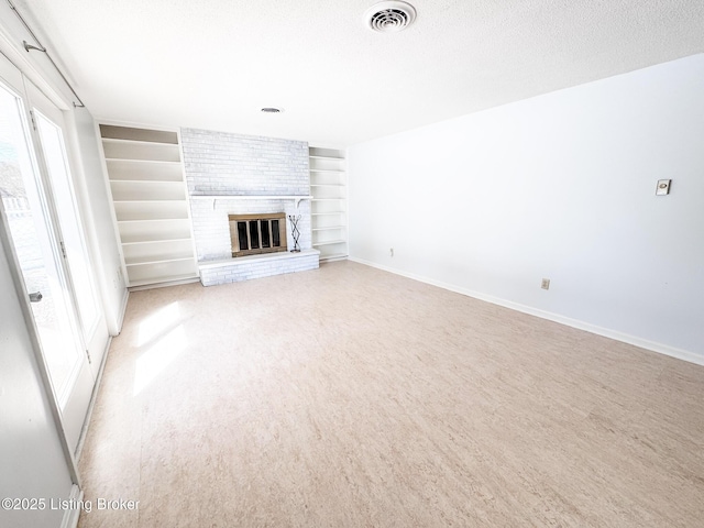 unfurnished living room with baseboards, visible vents, a textured ceiling, a brick fireplace, and built in shelves