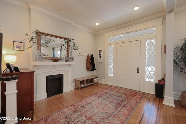 entryway featuring a fireplace, baseboards, crown molding, and wood finished floors