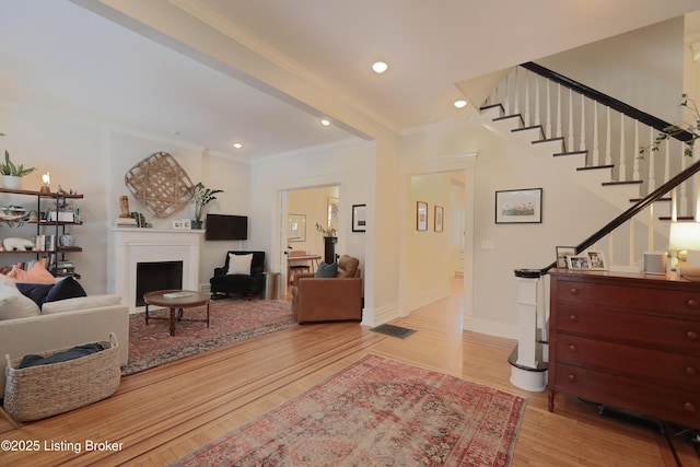 interior space featuring crown molding, a fireplace, recessed lighting, light wood-style floors, and stairs