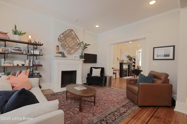 living room featuring ornamental molding, wood finished floors, a fireplace with flush hearth, and baseboards