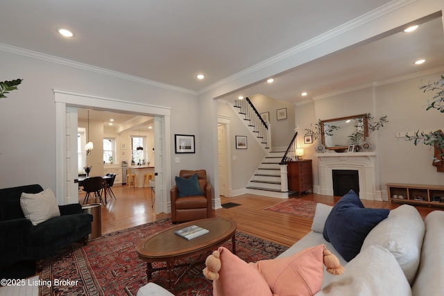 living room featuring stairs, wood finished floors, and crown molding