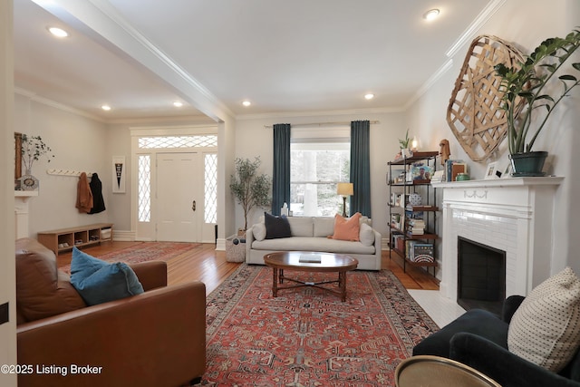 living area featuring baseboards, crown molding, light wood-style floors, a fireplace, and recessed lighting