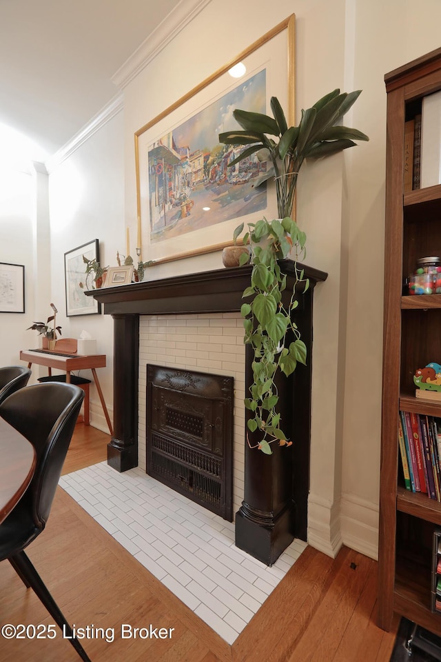 interior space with light wood-type flooring, a fireplace, crown molding, and baseboards