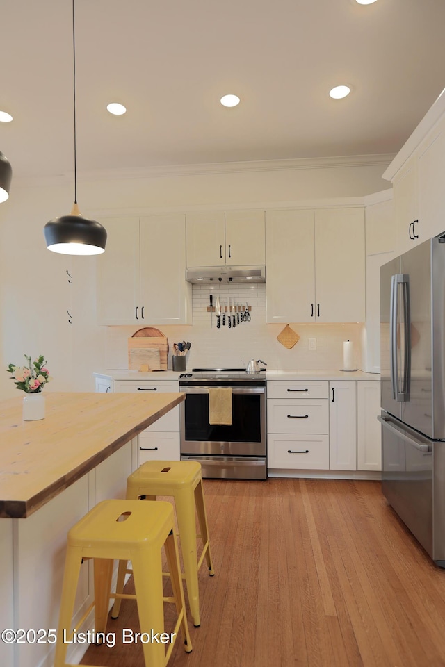 kitchen featuring white cabinets, under cabinet range hood, pendant lighting, and stainless steel appliances