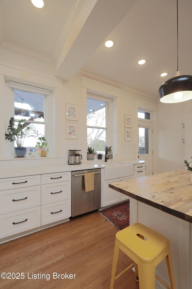 kitchen with hanging light fixtures, stainless steel dishwasher, butcher block counters, and white cabinetry