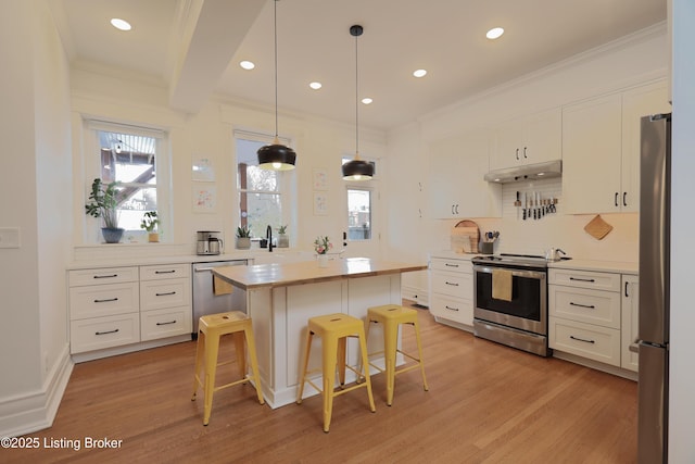 kitchen with a kitchen island, appliances with stainless steel finishes, a breakfast bar area, light countertops, and white cabinetry