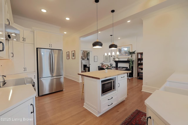 kitchen featuring a center island, a fireplace, light countertops, appliances with stainless steel finishes, and white cabinetry