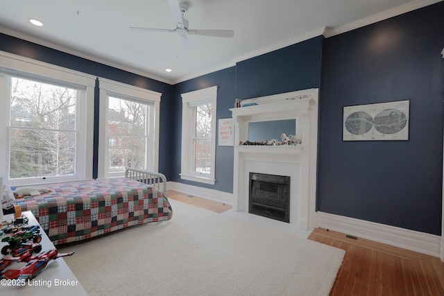 bedroom with a fireplace, recessed lighting, ornamental molding, light wood-type flooring, and baseboards